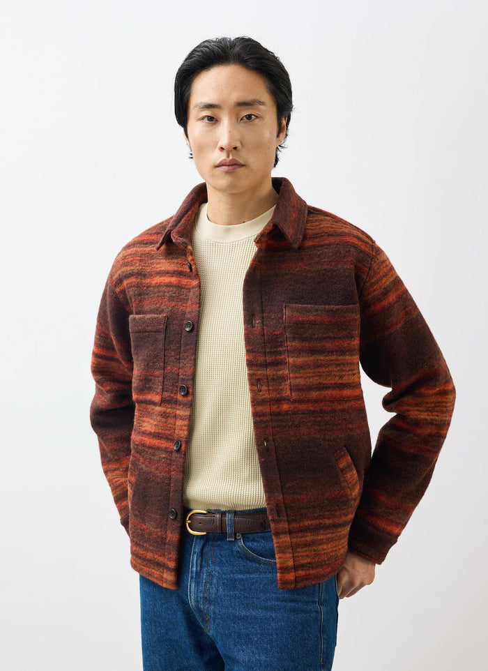 A model wears the Percival Mississippi Jacquard Overshirt in burnt orange and brown, styled with a cream t-shirt and jeans.