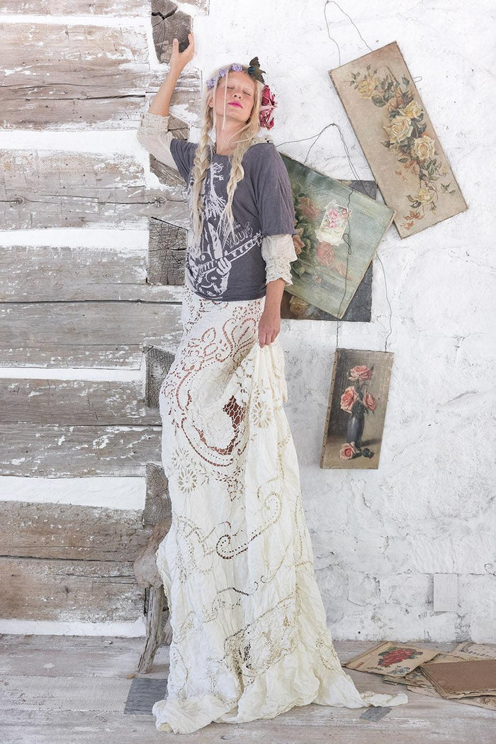 Magnolia Pearl artisan woman in vintage lace skirt, graphic tee, floral headpiece, rustic setting