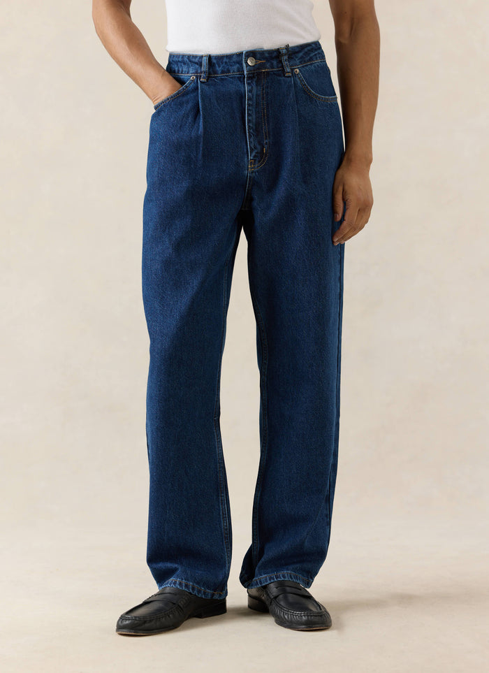 Mid-wash blue Percival pleated denim jeans in 12oz cotton, featuring a straight-leg fit and shown on a model.