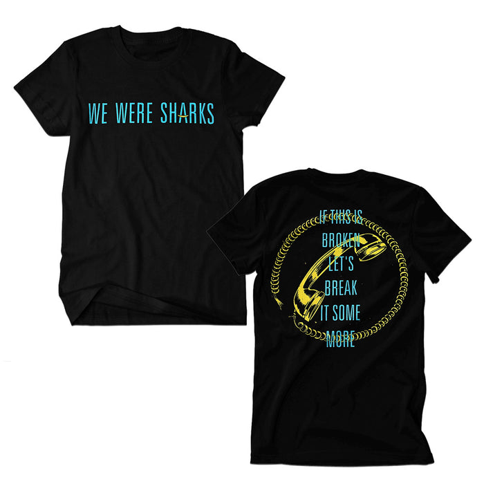 We Were Sharks black t-shirt featuring WE WERE SHARKS in blue on the front. Back displays a large yellow safety pin circle with blue text: IF THIS IS BROKEN, LET’S BREAK IT SOME MORE.