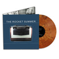 A marbled Copper Nugget Shimmer vinyl from The Rocket Summer partly slides out of a blue album cover with an old radio and THE ROCKET SUMMER text; this 25th anniversary edition also shows a black-and-white inner sleeve with photos.