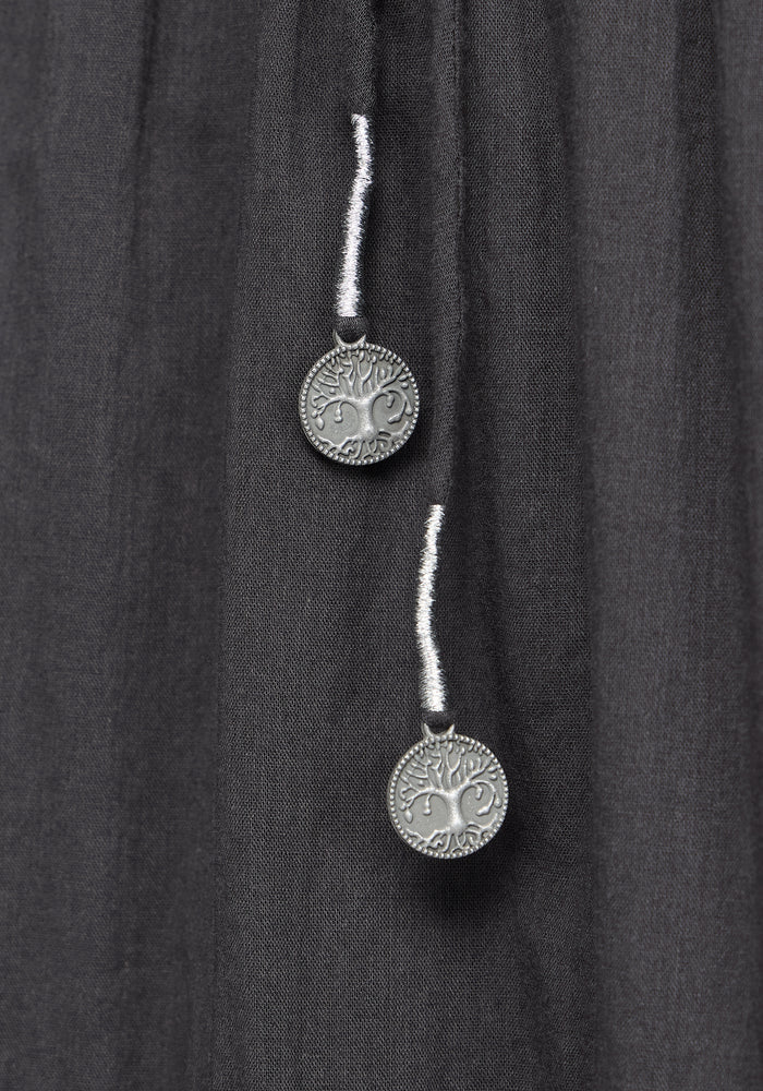 Close up detail of two silver pendants on a grey midi dress